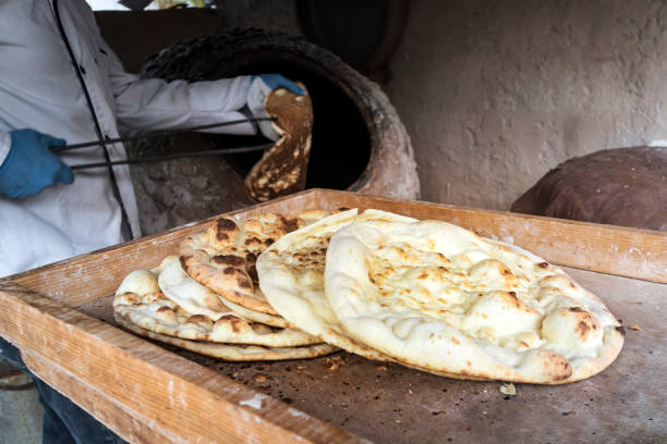 Large flat freshly baked tortillas lie on the table. Hot bread. Central Asian cuisine. aged man makes traditional bread in old round stone oven in rural village. aged man makes traditional bread in old round stone oven in rural village. Large flat freshly baked tortillas lie on the table. Hot bread. Central Asian cuisine. armenia country stock pictures, royalty-free photos & images