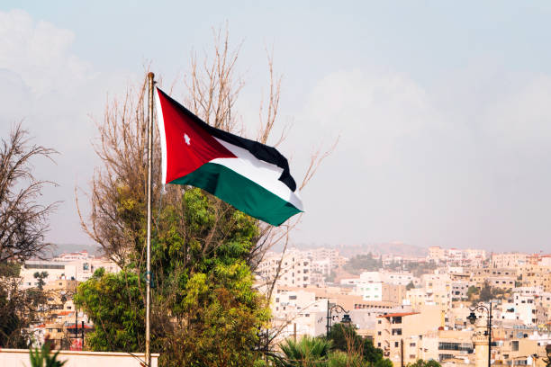 tricolor flag of Jordan on the background of the old poor of the city and blue sky. tricolor flag of Jordan on the background of the old poor of the city and blue sky borough district type photos stock pictures, royalty-free photos & images