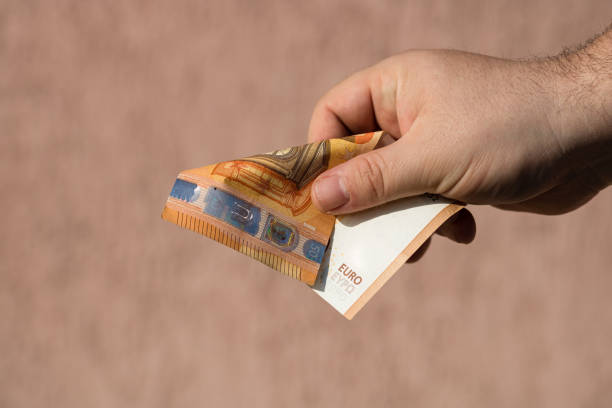 istock Man hands giving money like a bribe or tips. Holding EURO banknotes on a blurred background, EU currency 1203967006