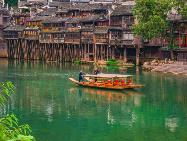 Unacquainted tourist sightseeing fenghuang old town architecture by boat in the river. fenghuang,Hunan/China-16 October 2018:Unacquainted tourist sightseeing fenghuang old town architecture by boat in the river.phoenix ancient town or Fenghuang County is a county of Hunan Province, China fenghuang county photos stock pictures, royalty-free photos & images