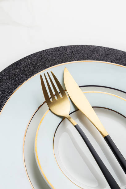 istock Close up side view gold fork and knife on plate 1203969106