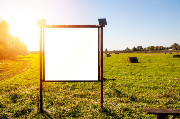 istock Blank white advertisement/annoucement board on the meadow. Sunny autumn day 1203969704