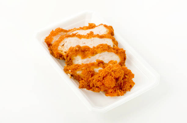 Sliced breaded chicken breast on a Styrofoam tray on white background