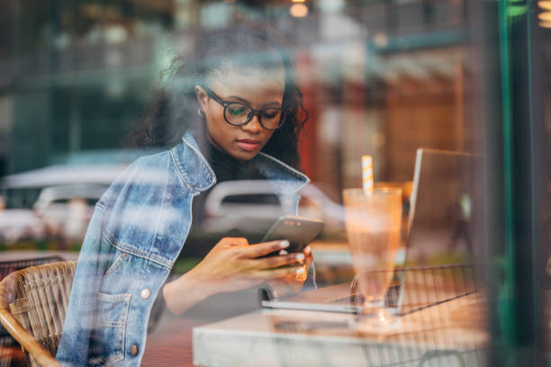 istock Black woman sitting alone in cafe and using mobile phone 1203971580