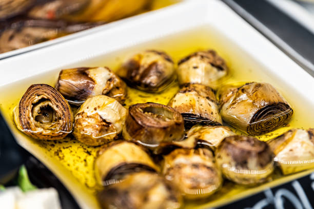 alcachofas marinadas a la parrilla verduras en aceite de oliva en la tienda de mercado exhibición de comestibles en florencia italia macro primer plano - artichoke vegetable macro close up fotografías e imágenes de stock