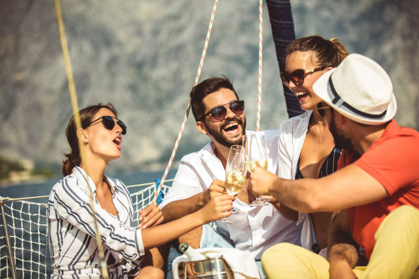 lächelnde freunde mit gläsern champagner auf der yacht. - horizontal gestreiften vorhängen stock-fotos und bilder