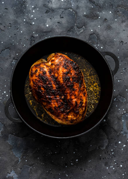 istock Simple baked chicken breast in a cast iron pan on a dark background, top view 1203980629