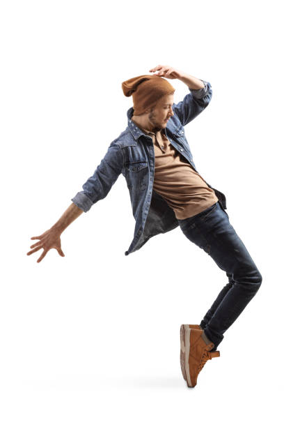 istock Young guy in jeans and woolen hat dancing on tiptoes 1203982735