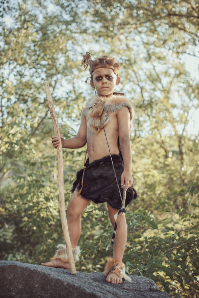 istock Caveman, manly boy with staff and bow hunting outdoors. Ancient warrior 1203982781