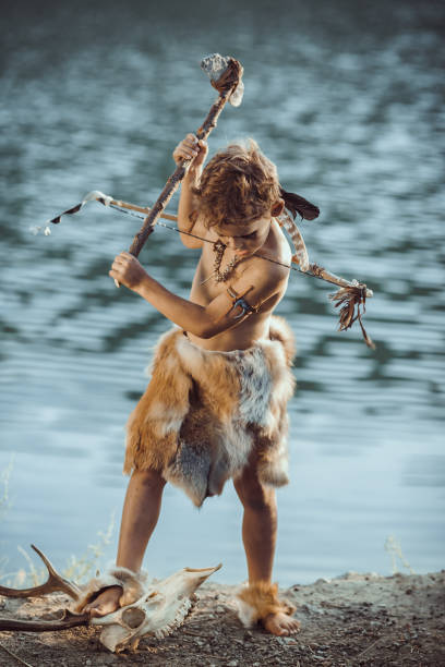 istock Angry caveman, manly boy with ancient primitive weapon hunting outdoors. Ancient prehistoric warrior. Heroic movie look 1203982884