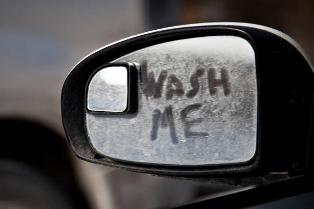 Wash me inscription ondirty car mirror