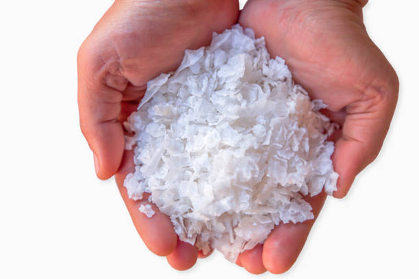 Pure white crystal salt or rock salt in woman hands isolated on white background with clipping path.