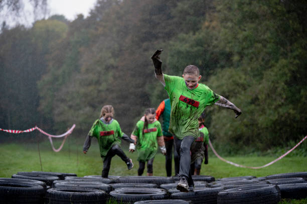 This Is How You Do It A young boy shows his teammates how it's done and leads the group on the tire track part of the obstacle course. youth sports competition stock pictures, royalty-free photos & images