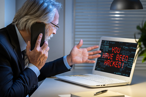 Sad businessman looking at computer monitor with inscription You have been hacked. Cybercrime concept.