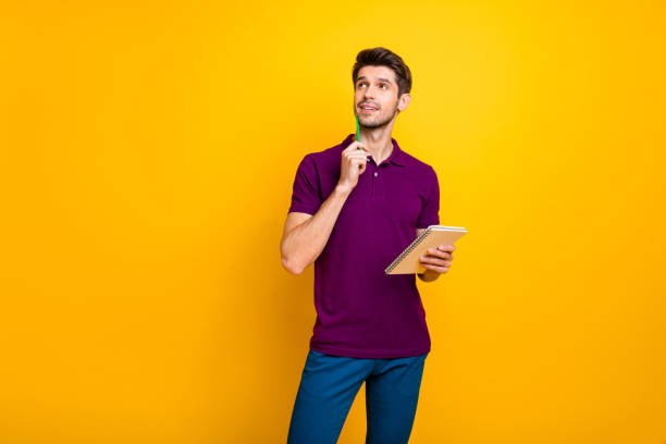 istock Portrait of his he nice attractive minded focused concentrated guy creating making notes exercise book isolated over bright vivid shine vibrant yellow color background 1203986948