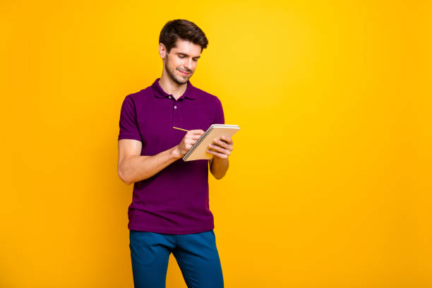 istock Portrait of his he nice attractive cheerful cheery focused concentrated guy making writing notes memo isolated over bright vivid shine vibrant yellow color background 1203990356