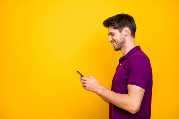 istock Profile side view portrait of his he nice attractive lovely cheerful cheery focused guy using cell sharing media isolated over bright vivid shine vibrant yellow color background 1203990477