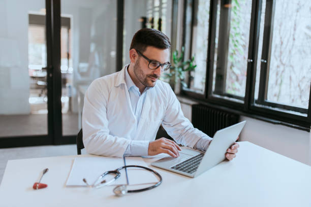 istock Handsome doctor working on laptop in the office, portrait. 1203992573