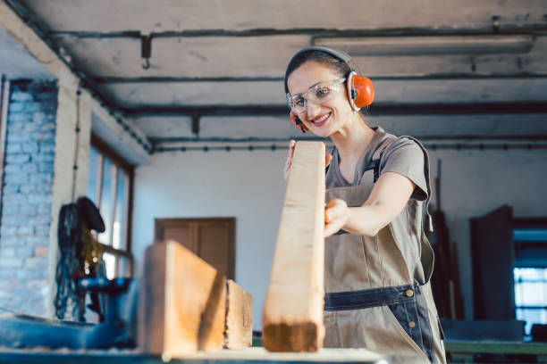 istock Beautiful woman carpenter checking quality of a plank 1203993668