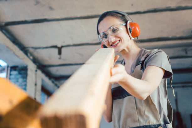 istock Beautiful woman carpenter checking quality of a plank 1203993709