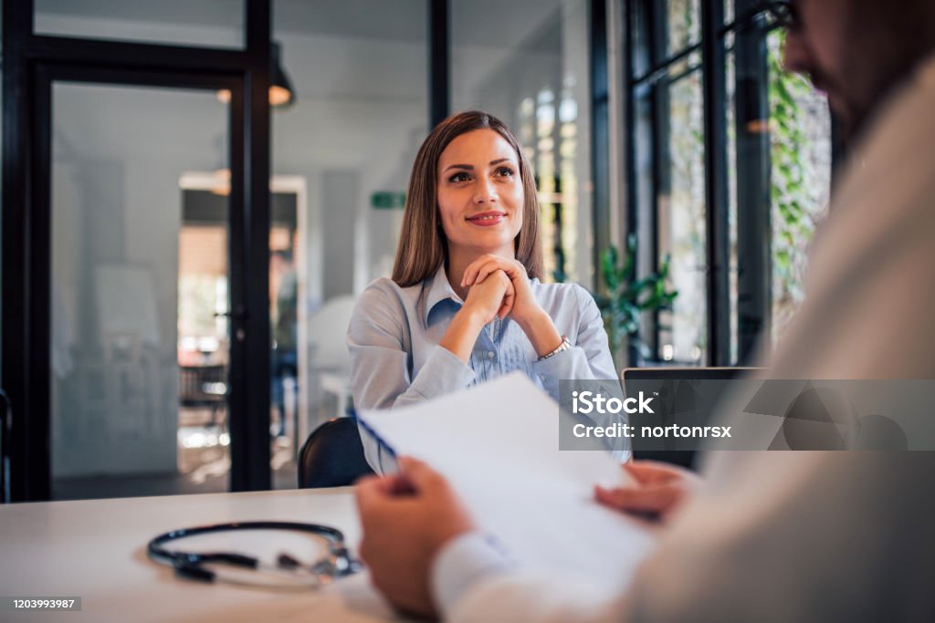 Portrait of a smiling woman at doctors office, receiving good news. Job Interview Stock Photo