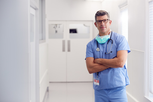 Retrato de médico masculino maduro usando exfoliantes de pie en el pasillo del hospital photo