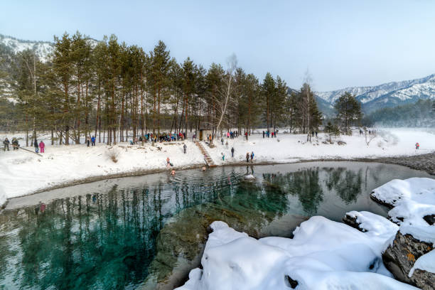 beautiful not frozen mountain lake among snow-capped mountains and trees in winter. The reflection in the water