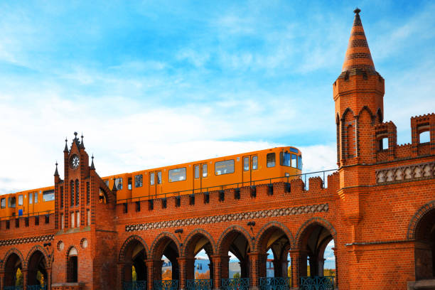 low angle view on yellow metro train on ion elevated subway track in Berlin Kreuzberg against blue sky