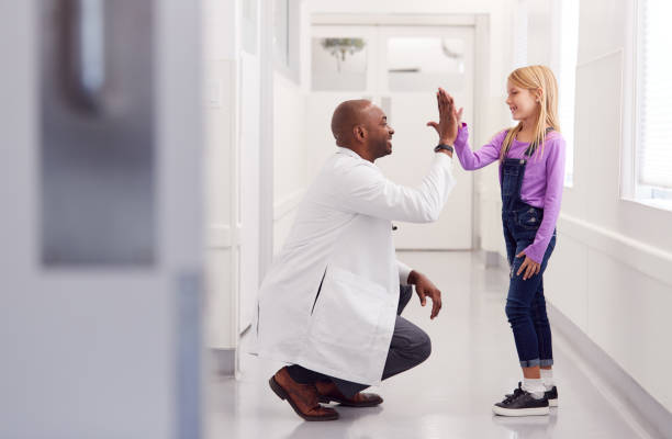 médico pediátrico masculino dando joven paciente paciente alto cinco en el corredor del hospital - doctor cheerful child healthcare and medicine fotografías e imágenes de stock