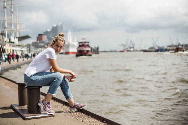 Blond girl enjoying fresh air Female tourist taking a break while sitting on a dock ancor hamburg stock pictures, royalty-free photos & images