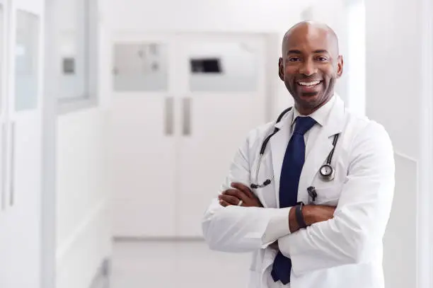 Photo of Portrait Of Mature Male Doctor Wearing White Coat Standing In Hospital Corridor