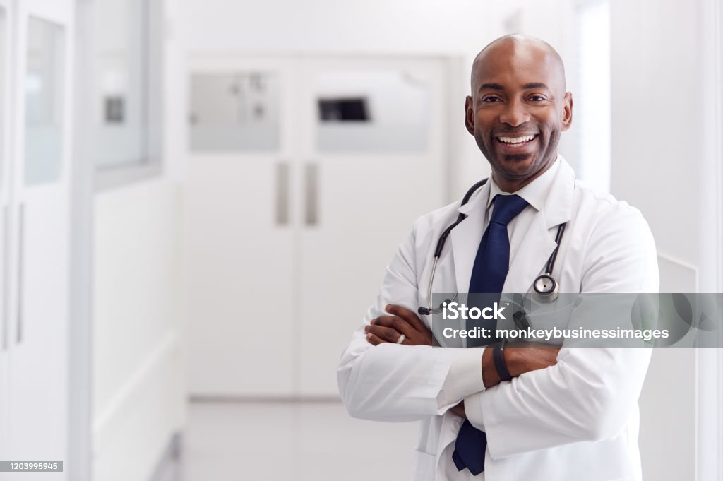 站在醫院走廊的成熟男醫生穿白色外套的肖像 - 免版稅醫生圖庫照片