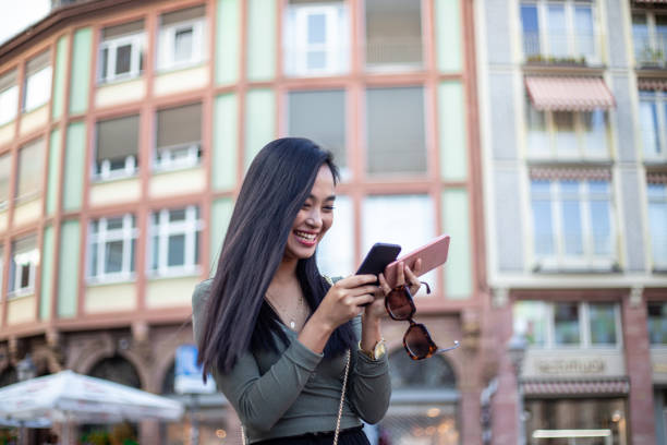 istock Happy asian woman text messaging while on vacation 1203996642