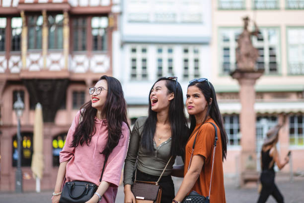 istock Three female friends joking and bonding while standing in a city centre 1203996737
