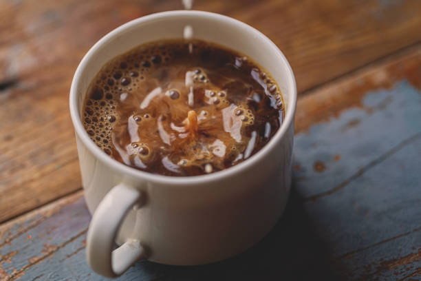 istock Milk Drip Into Coffee On Wood Board 1203996981