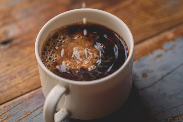 istock Milk Drip Into Coffee On Wood Board 1203997213