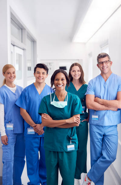 портрет улыбающейся мультикультурной медицинской команды, стоящей в больничном коридоре - вертикальный стоковые фото и изображения