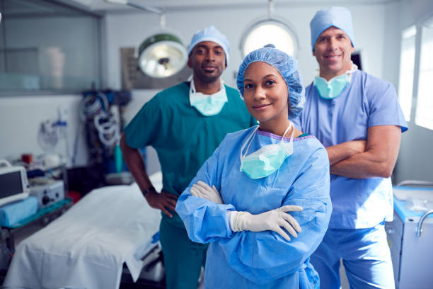 portrait of multi-cultural surgical team standing in hospital operating theater - cirurgia imagens e fotografias de stock