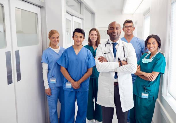 Portrait Of Multi-Cultural Medical Team Standing In Hospital Corridor Portrait Of Multi-Cultural Medical Team Standing In Hospital Corridor medical occupation stock pictures, royalty-free photos & images