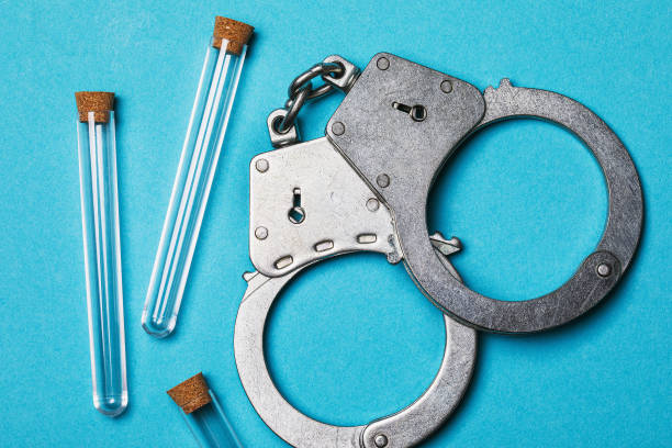 istock Handcuffs and medical flasks on a blue background, top view. Laboratory error concept 1204002018
