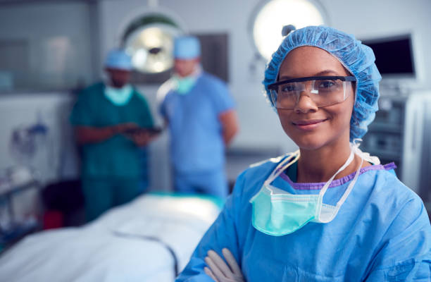 portrait of female surgeon wearing scrubs and protective glasses in hospital operating theater - surgeon imagens e fotografias de stock