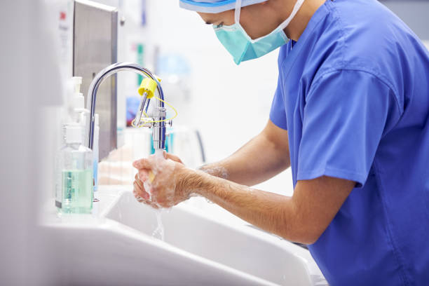 cirujano masculino que usa exfoliantes en lavarse las manos antes de operar en el quirófano del hospital - communicable disease fotografías e imágenes de stock