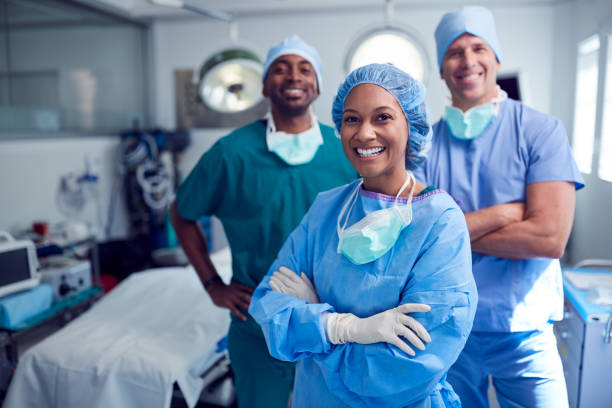 Portrait Of Multi-Cultural Surgical Team Standing In Hospital Operating Theater Portrait Of Multi-Cultural Surgical Team Standing In Hospital Operating Theater anaesthetist stock pictures, royalty-free photos & images