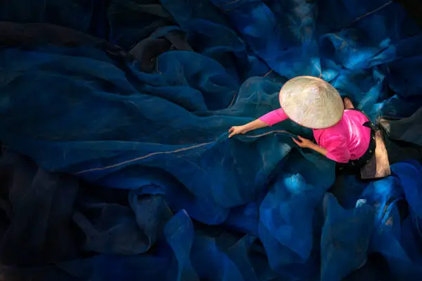 woman sew the fishnet. Fisherman Repairs Fishing Net. Needle with thread in fisherman hand repairing net in home.