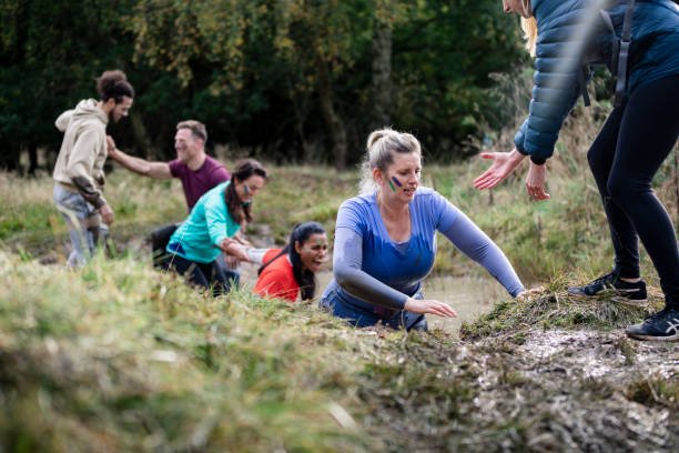 istock Competitors walking through muddy stream for charity event 1204006895