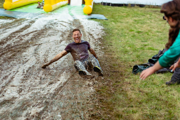 istock Mid adult man having fun on muddy slip and slide 1204006952