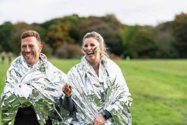 istock Happy runners relaxing with foil blankets after country run 1204006957