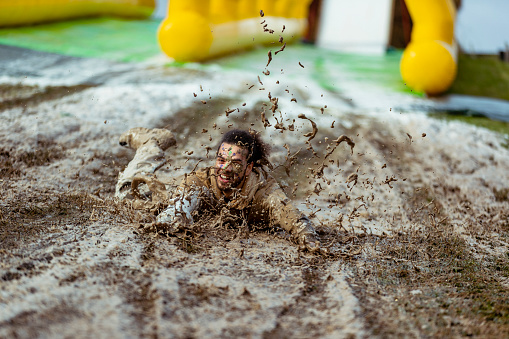 Cheerful mid adult man playing in the mud at charity event, fun, carefree, young at heart