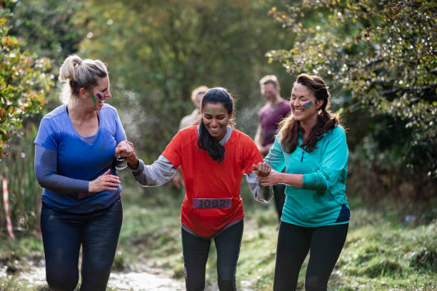 istock Cheerful women supporting friend along muddy track 1204007036