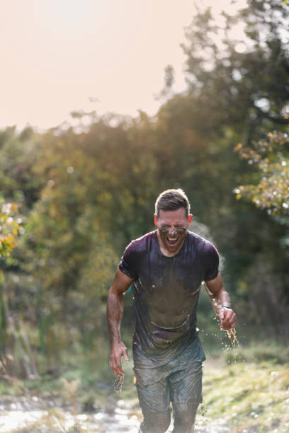 istock Muddy man with muscular build running through countryside 1204007133